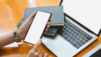 Close-up female holding her smartphone on office desk.