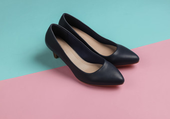 Fototapeta premium Classic leather high heel shoes on a pastel pink-blue background. Minimalistic fashion still life. Studio shot