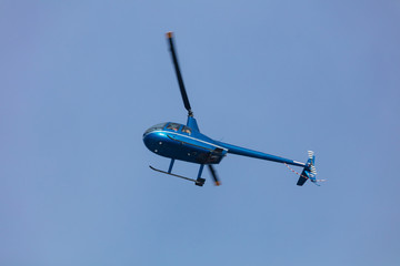 bright blue and small helicopter flying with passengers on blue sky background. helicopter rides in...