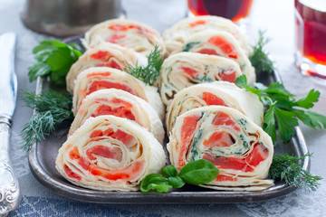 Lavash roll with red fish and cheese on a metal dish, horizontal