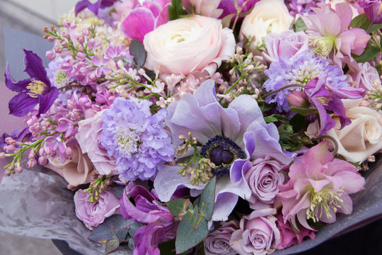 Pink purple blue wedding bouquet by florist with different flowers and roses close-up. Floral background	
