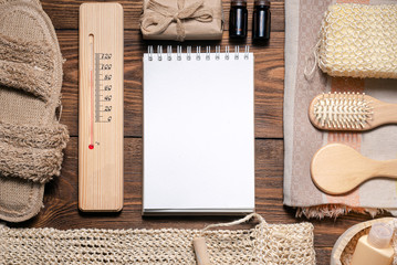 Bath house accessories and blank page notepad on brown wooden flat lay background with copy space....