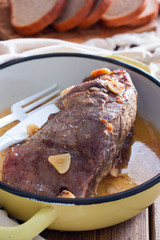 Baked beef fillet with pieces of garlic in a pan, selective focus
