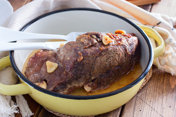 Baked beef fillet with pieces of garlic in a pan, horizontal