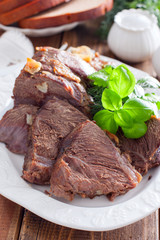 sliced baked beef fillet on a white dish with fresh herbs, selective focus