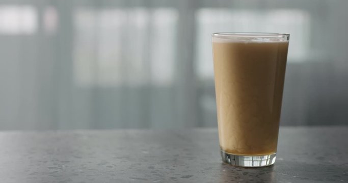 Slow motion nitro light ale beer with beautiful foam in pint glass on terrazzo countertop with window on background