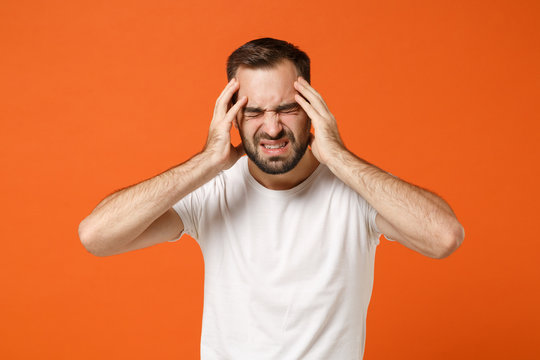 Exhausted young man in casual white t-shirt posing isolated on orange background studio portrait. People sincere emotions lifestyle concept. Mock up copy space. Put hand on head, keeping eyes closed. - Powered by Adobe