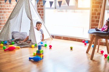 Beautiful toddler boy sitting on the floor playing inside  tipi at kindergarten © Krakenimages.com