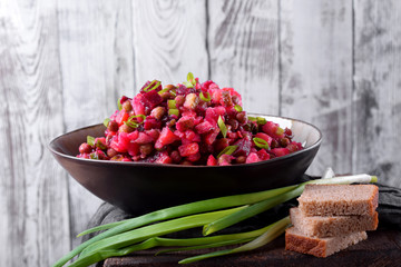 Vinaigrette salad in a ceramic bowl against the white wooden wall. Russian cuisine meal