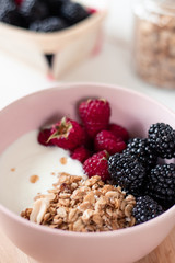 Breakfast with yogurt, berries and granola on a light background.