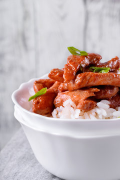 Pieces of meat in tomato sauce with spices on rice in a white bowl