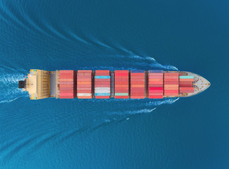 Aerial top view container cargo ship full speed with beautiful wave pattern for business logistics, import export, shipping or transportation.