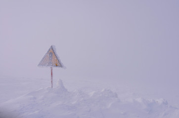 Sign "attention" covered with snow.