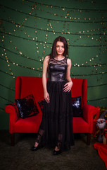  beautiful girl in a black dress stands near the elegant red sofa