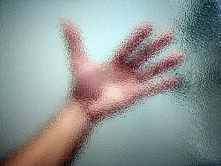 Hands touching frosted glass. Silhouette of a hand through frosted glass. Conceptual scream for help, depression, stress, panic