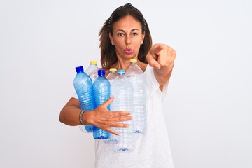 Middle age beautiful woman recycling plastic bottles standing over isolated white background pointing with finger to the camera and to you, hand sign, positive and confident gesture