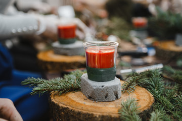 making Christmas decorations from red candles, Christmas tree branches and cones