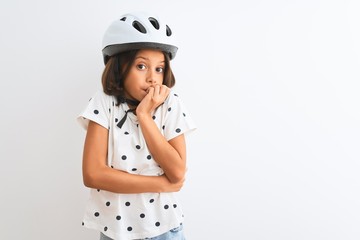 Beautiful child girl wearing security bike helmet standing over isolated white background looking stressed and nervous with hands on mouth biting nails. Anxiety problem.