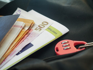 Passport, cash, boarding pass and small travel lock on a dark travel bag, concept: travel items, preparation.