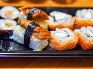 Great selection of different kind of sushi on a black plate on a wooden table, Selective focus.