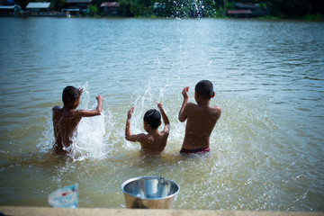 Three boys are playing water in the river, Thailand, southeast Asia.  