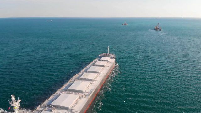 The large cargo vessel left the port after loading and moves in the right direction at high speed. Balker goes in the ocean.