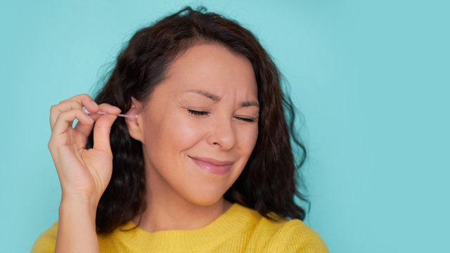 ear care. woman cleans her ear with a cotton swab. cotton swab injury