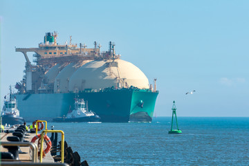 Barco mercante para el transporte de gas entrando a puerto acompañado de remolcadorescarga