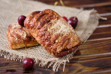 Puffs with cherry jam on burlap on a wooden background. Rustic style