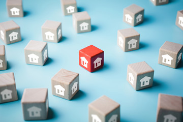 Unique red wooden block in group of wooden blocks with house icons on blue background, select the house or real estate concept