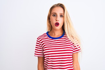 Young beautiful woman wearing red striped t-shirt standing over isolated white background afraid and shocked with surprise expression, fear and excited face.