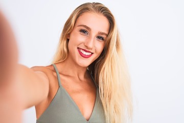 Young beautiful woman wearing t-shirt make selfie by camera over isolated white background with a...