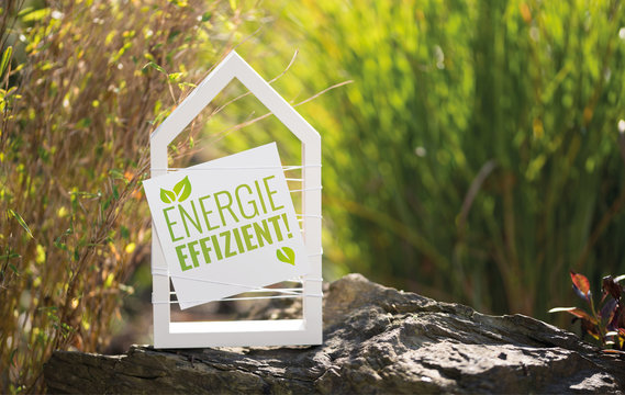 Wei&szlig;es Haus im Garten mit Schild Energieeffizient!