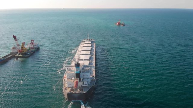 The large cargo vessel left the port after loading and moves in the right direction at high speed. Balker goes in the ocean.