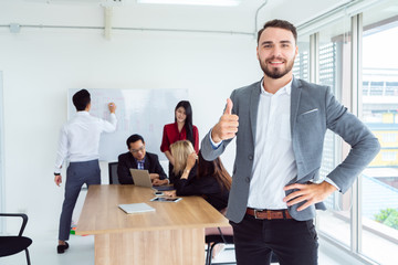 Portrait of businessman with colleagues in meeting in background at the office.Male Executive With Office Meeting In Background.