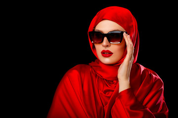 Beautiful Luxury Girl in Red Hijab. isolated. Red Lips. Fashionable young Arabic  Woman in sun-protected glasses. Bride. Arab Traditions. Beautiful Arab Girl on black background  