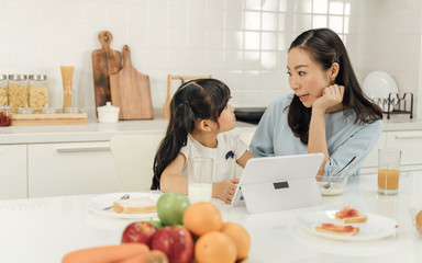 Healthy food at home and Happy family in the kitchen concept. Mother and child daughter are having breakfast.Cute little girl and her beautiful parents are making breakfast while cooking in kitchen.
