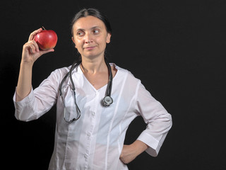 Doctor woman emotionally posing with Apple in hand on black background