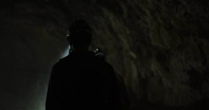 Slow motion in a smoky cave of two explorers shinning headlamps