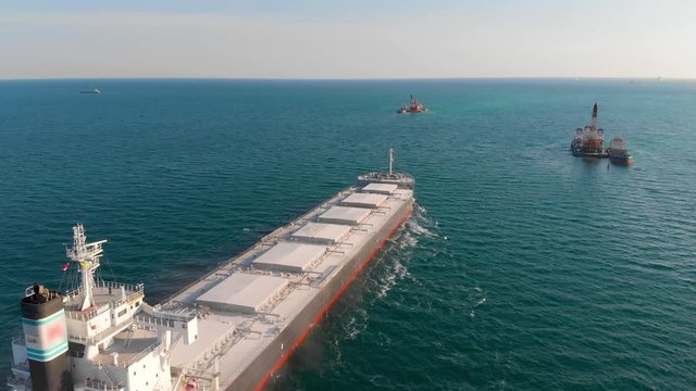The large cargo vessel left the port after loading and moves in the right direction at high speed. Balker goes in the ocean.