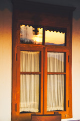 Wooden window in an old house at sunset