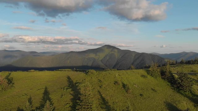 Aerial Drone Footage View: Flight over autumn mountain village with forest in sunrise soft light. Image processed in orange glow. Carpathian Mountains, Ukraine, Europe. Majestic landscape. Beauty.