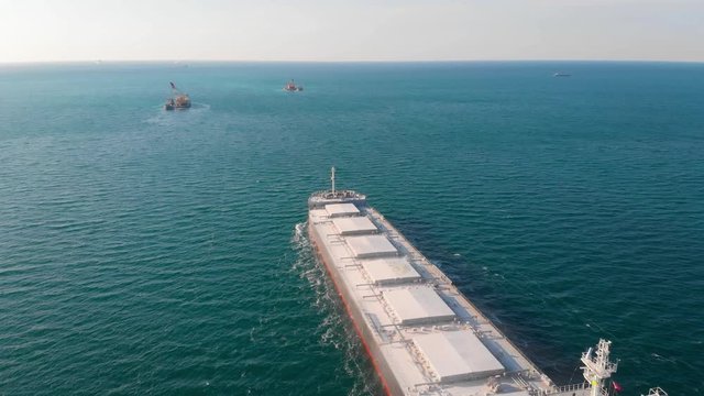 The large cargo vessel left the port after loading and moves in the right direction at high speed. Balker goes in the ocean.