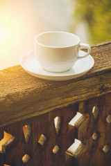 White cup on carved wooden railing