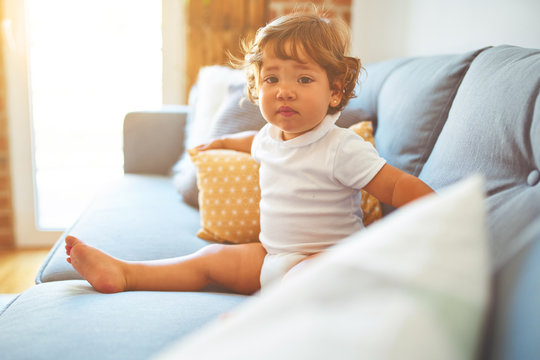 Beautiful toddler child girl wearing white t-shirt sitting on the sofa