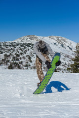 Young snowboarder riding in the mountains on a snowboard.