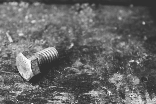  a steel screw on a wooden table
