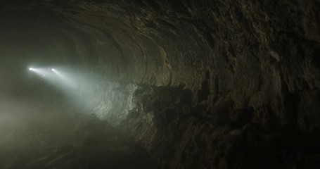 Reveal of two teammates on an adventure race team going through cave crane shot