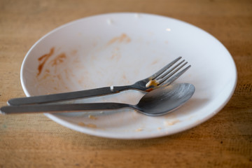 Dirty plate with spoon and fork after a meal