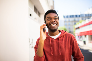 smiling african american man talking with cellphone outside